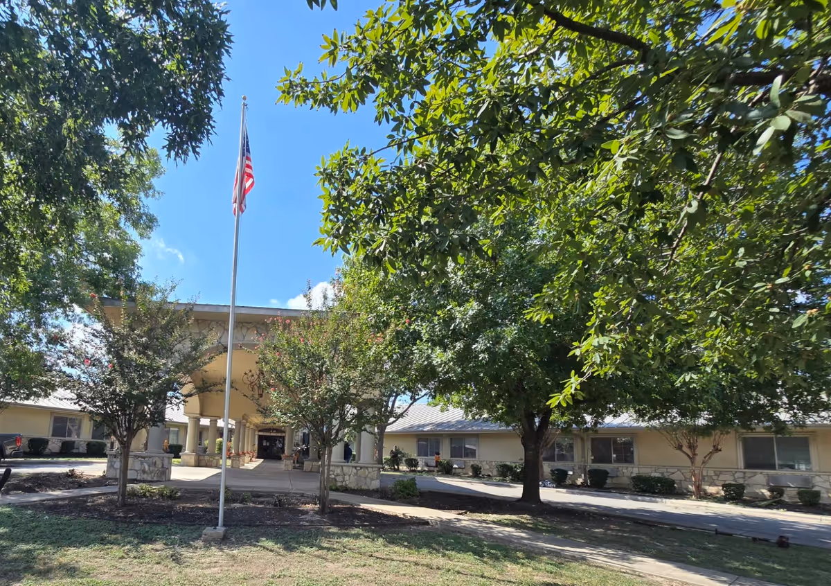 Exterior view of Regent Care at Medical Center with flagpole and trees.