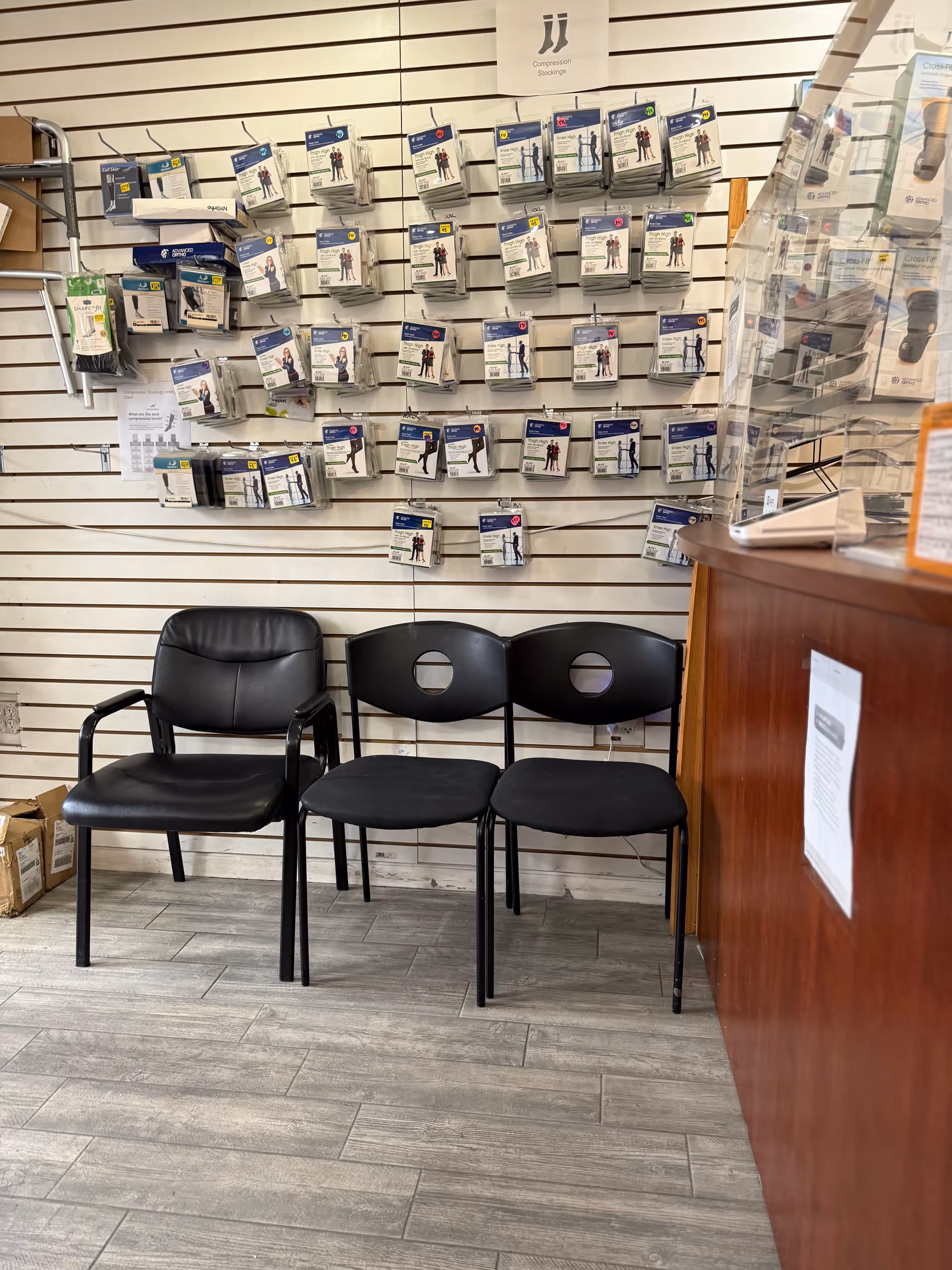 Wall display of medical supply packaging with three black chairs in a waiting area.