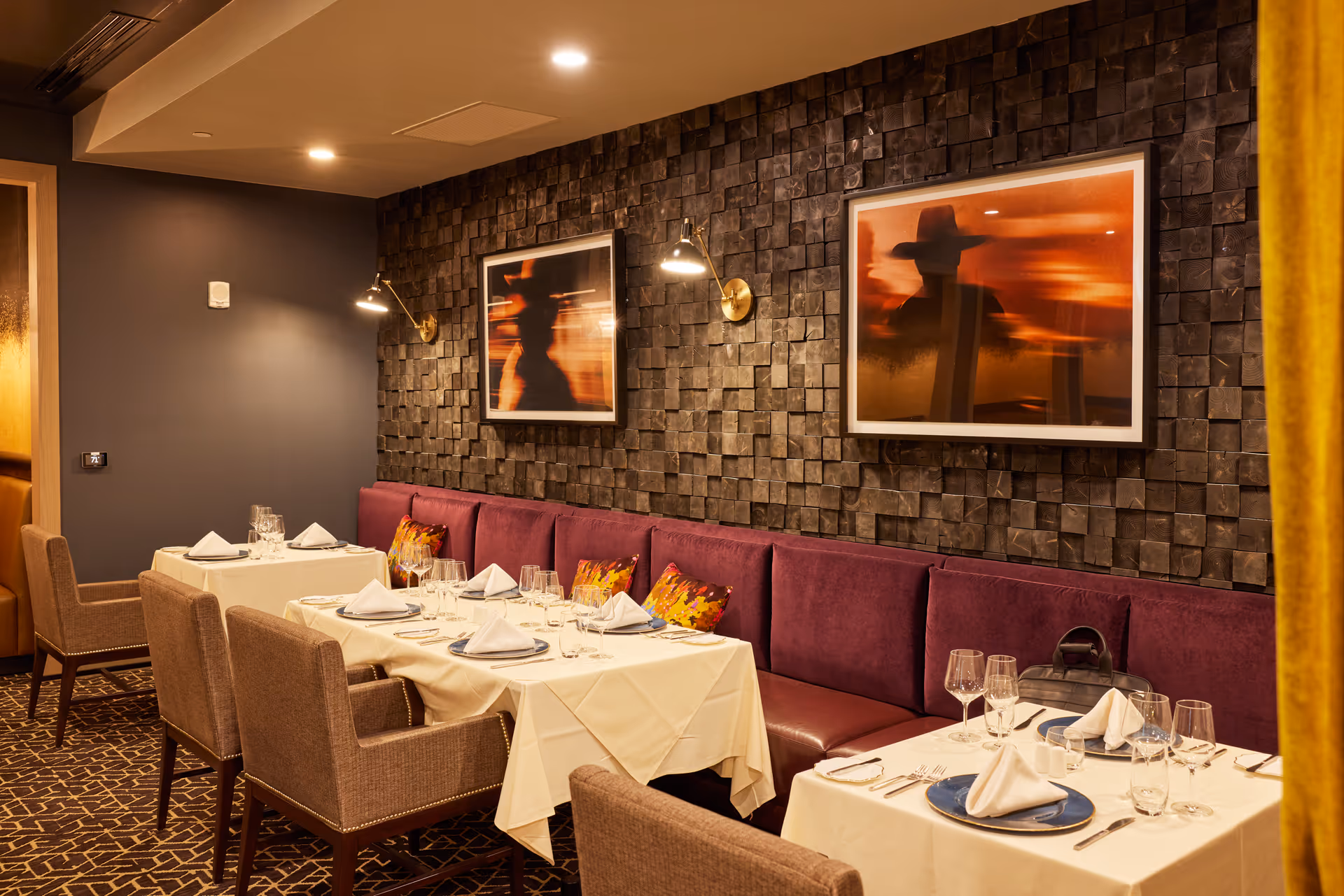 Elegant dining room with white-tablecloth tables, purple seating, and modern wall art.