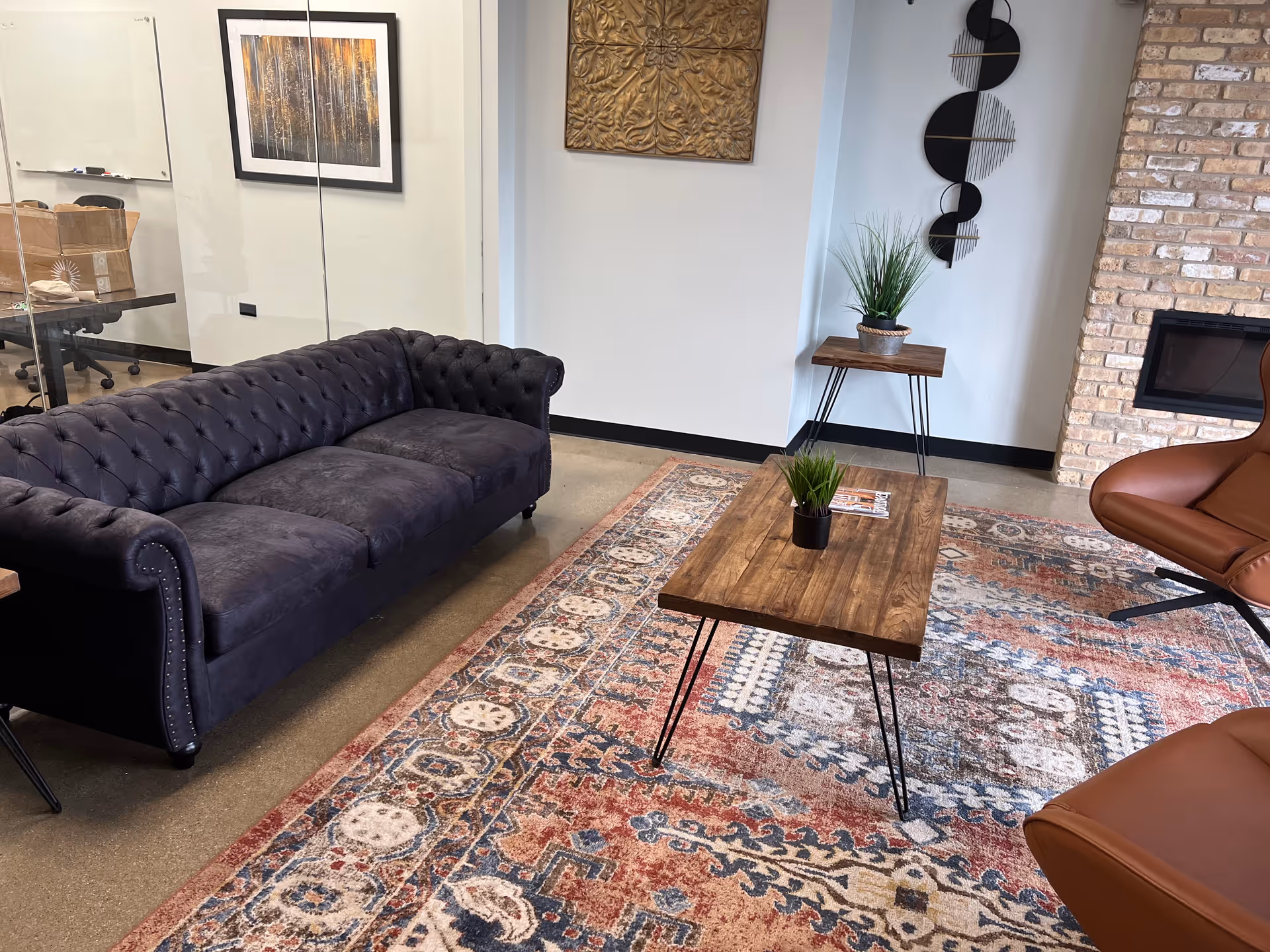 Cozy modern lounge with a tufted navy sofa, leather chairs, and a wooden coffee table.