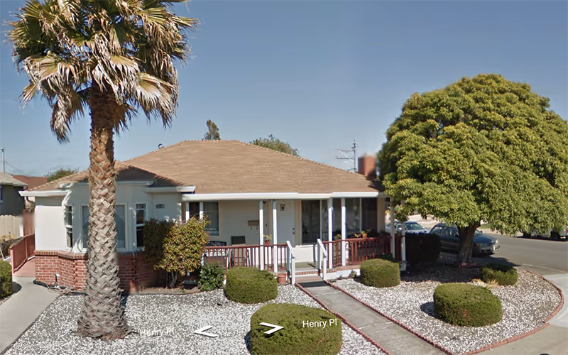 Heritage Royale exterior: a single-story facility with a front porch, palm tree, and trimmed landscaping.