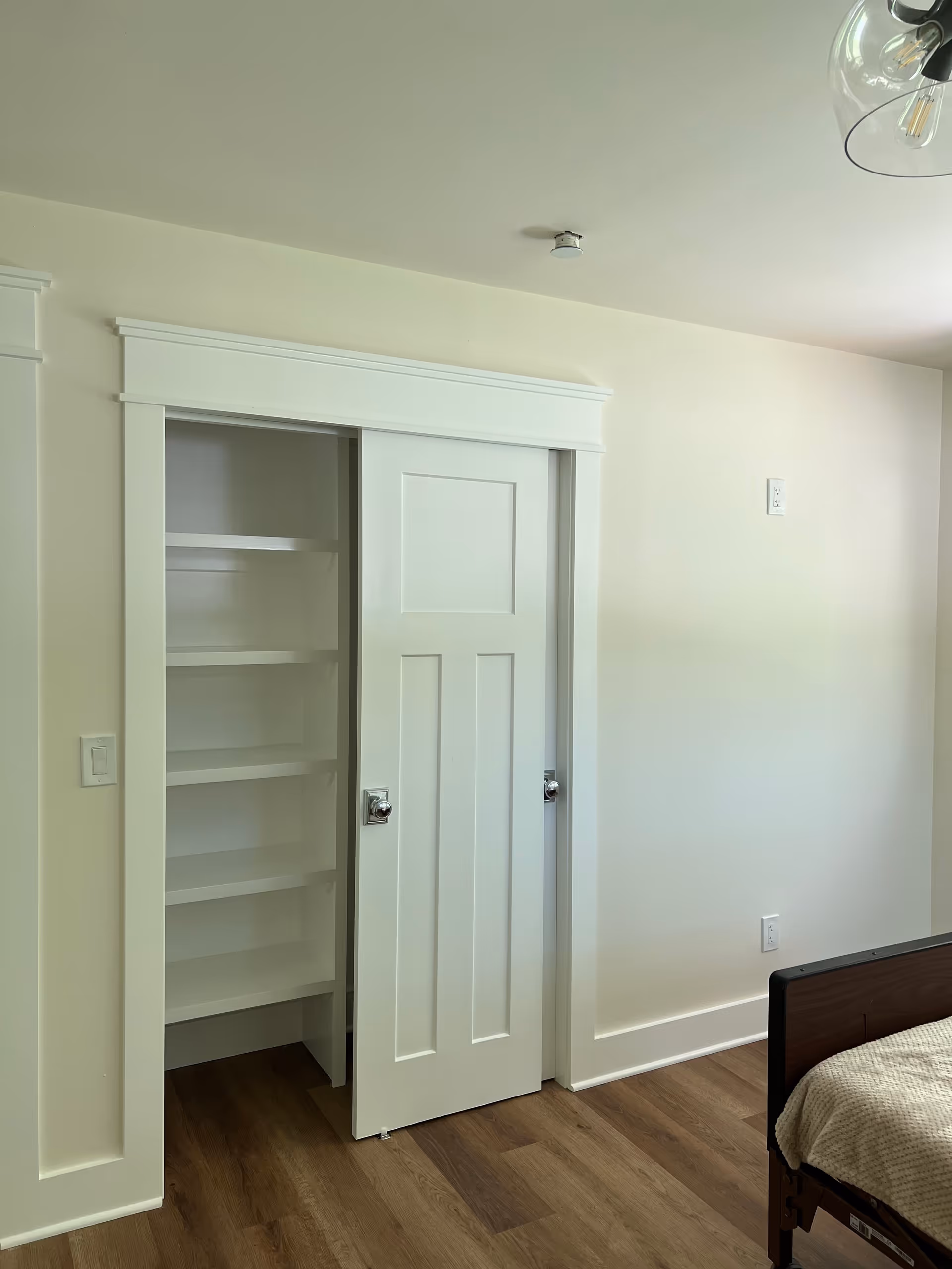 White bedroom with built-in closet shelves and a partial view of a bed