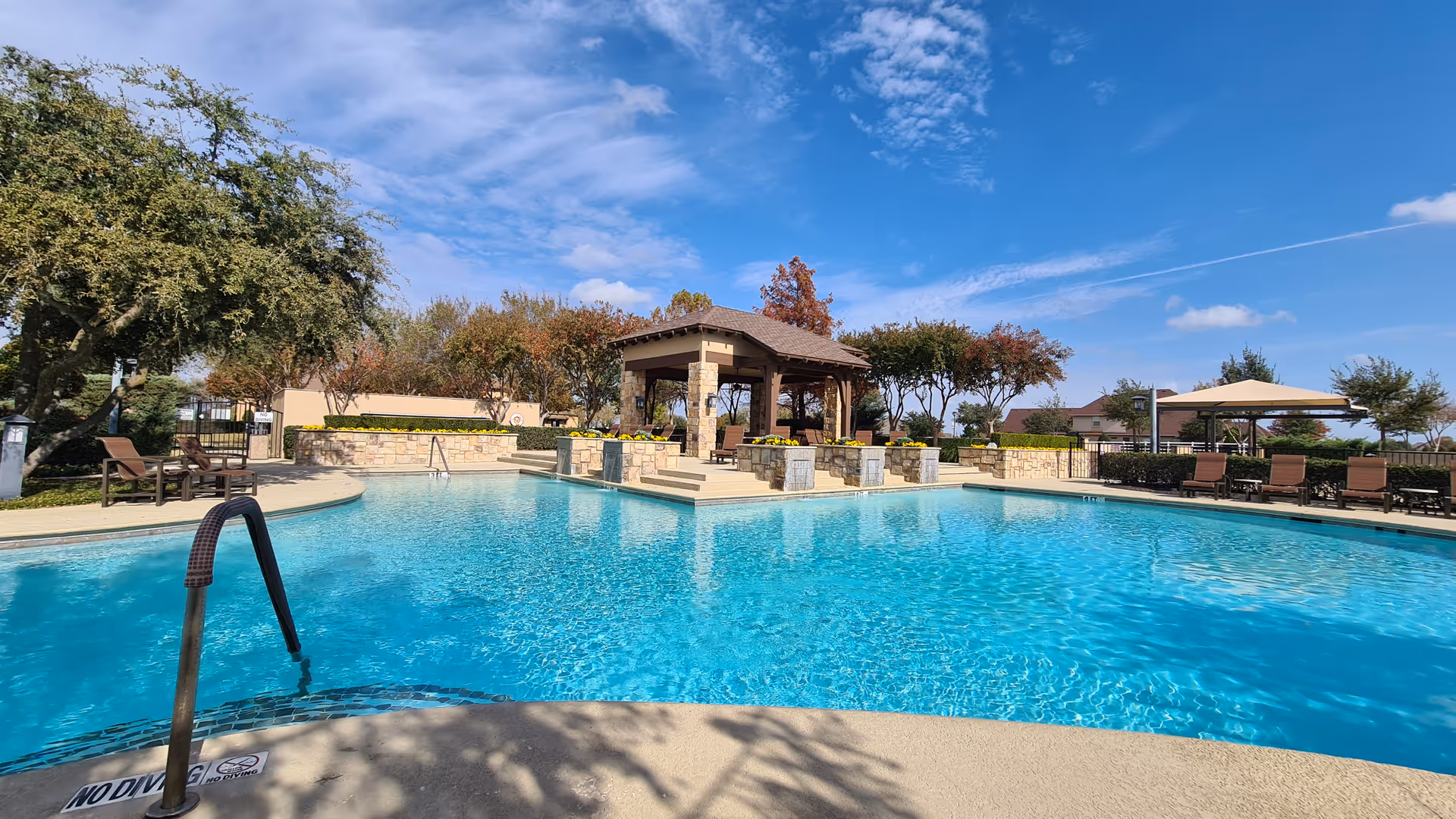 Sunny outdoor pool area at Robson Ranch Texas with a gazebo and lounge seating.