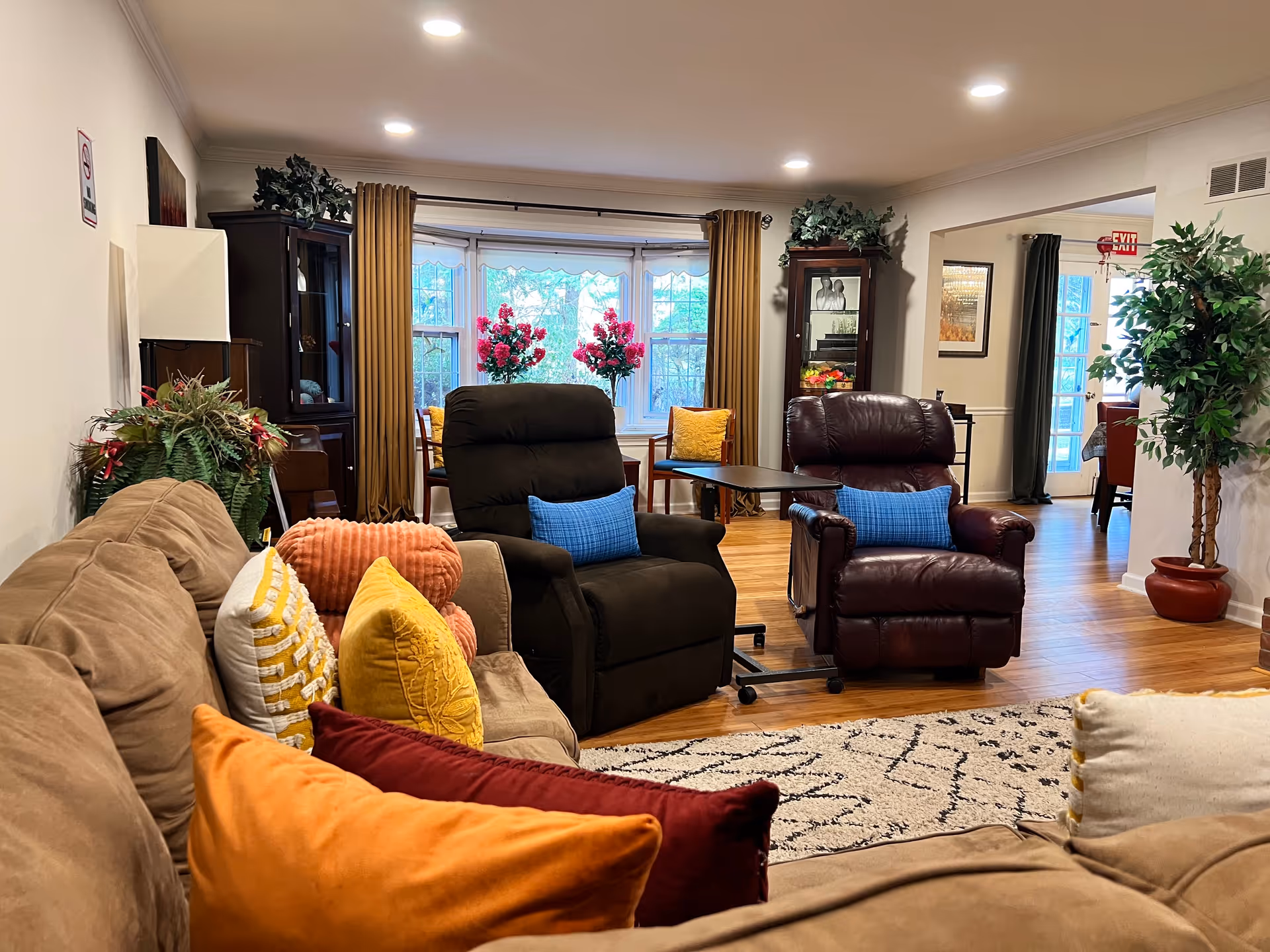 Cozy living room in a senior facility with recliners, sofa, decorative pillows, and plants.
