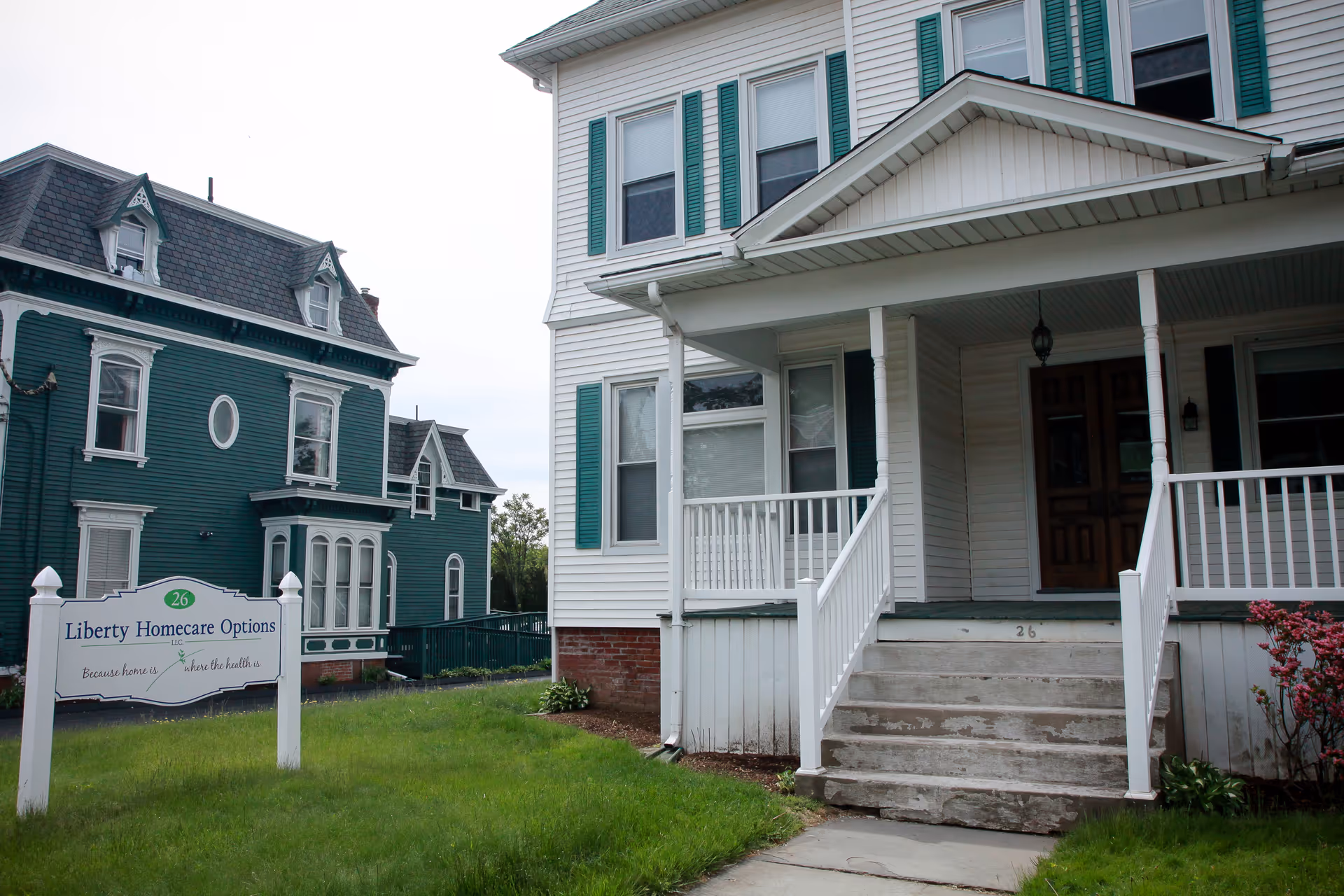 White porch-front building with green shutters and a Liberty Homecare Options sign in front yard.