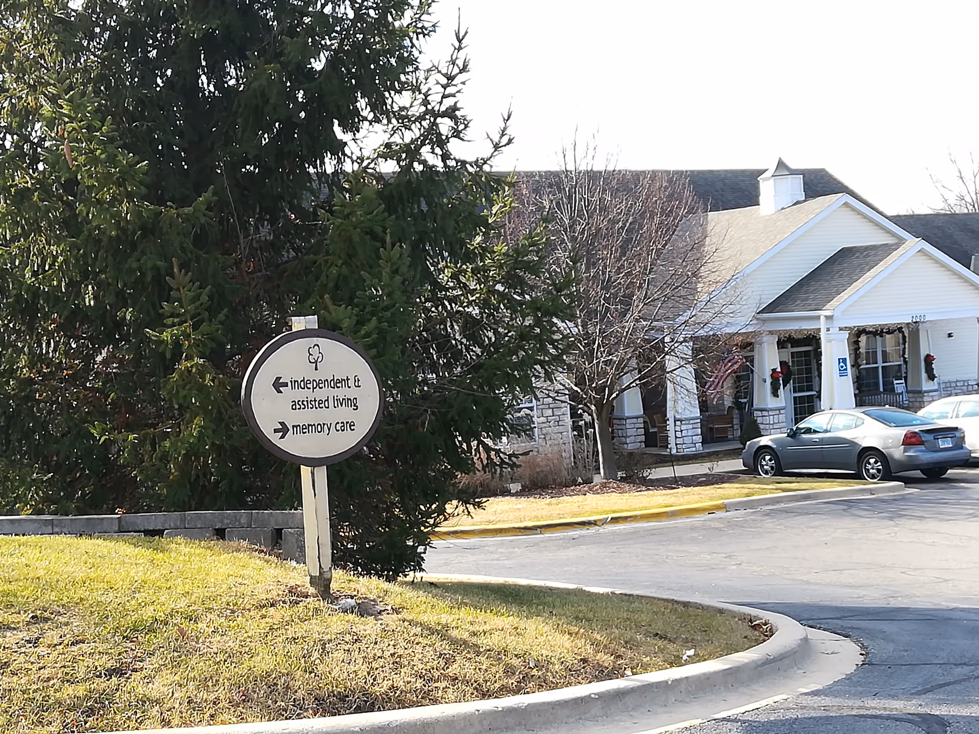 Exterior view of Bickford of Peoria with a circular sign and parked cars.
