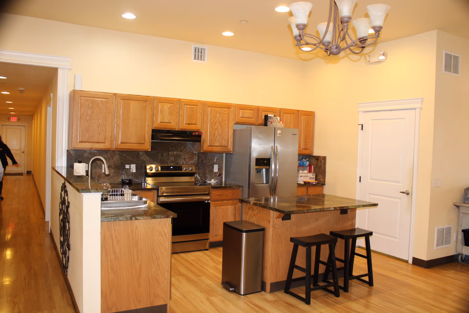 Open-concept kitchen with wooden cabinets, stainless appliances, and an island with two stools.