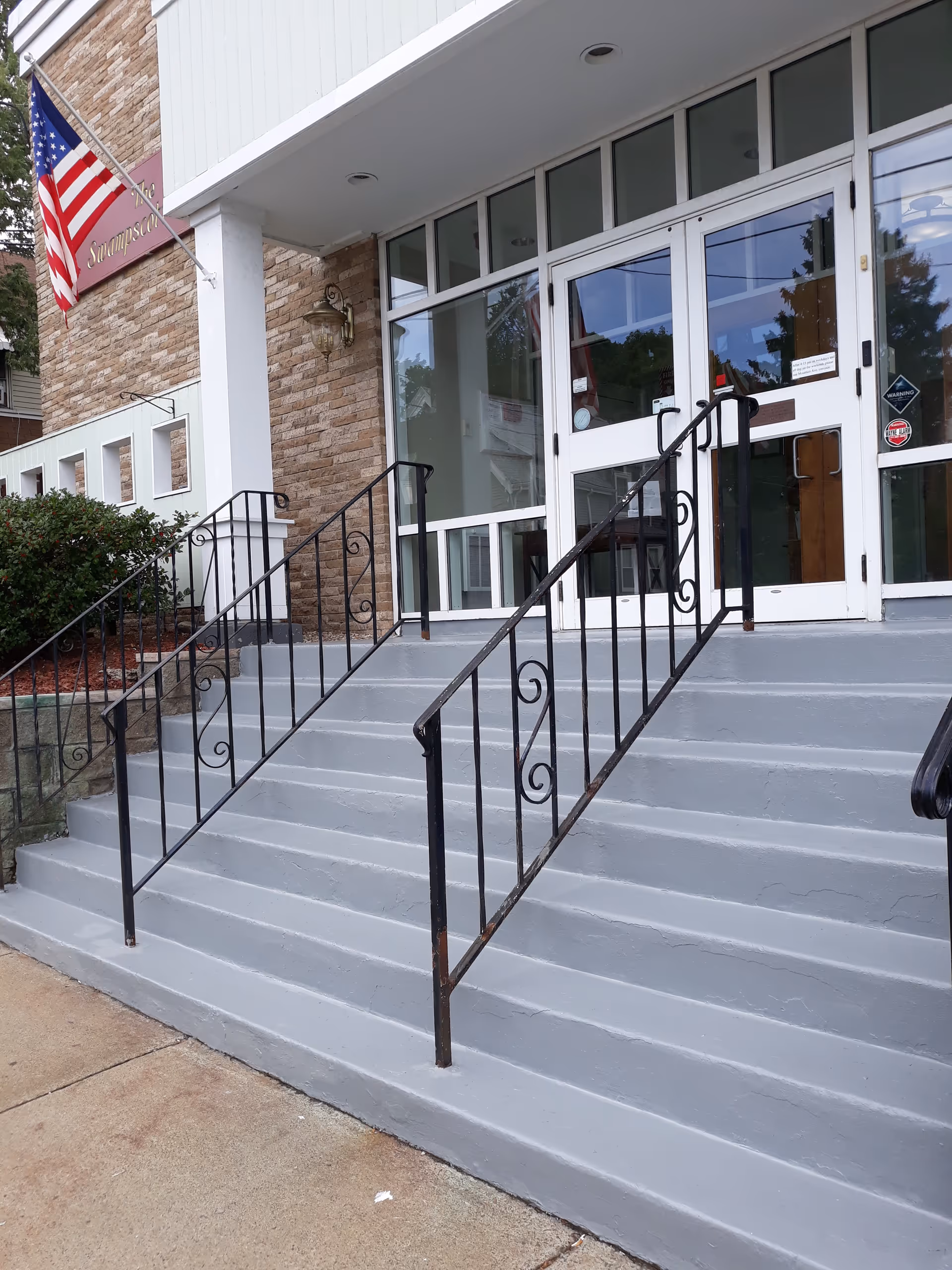 Front exterior of Abbott Skilled Nursing and Rehabilitation Center entrance with stairs and black railings.