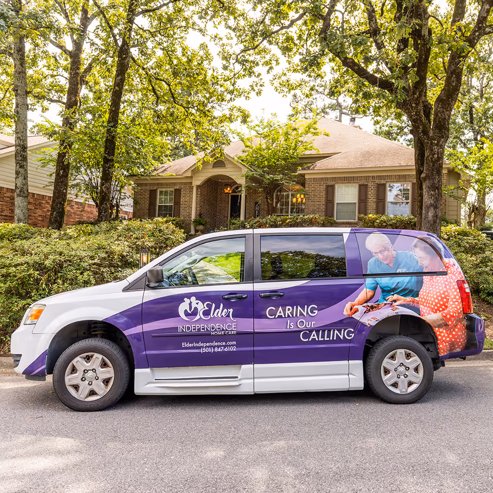 Purple Elder Independence Home Care van parked in front of a brick senior facility.