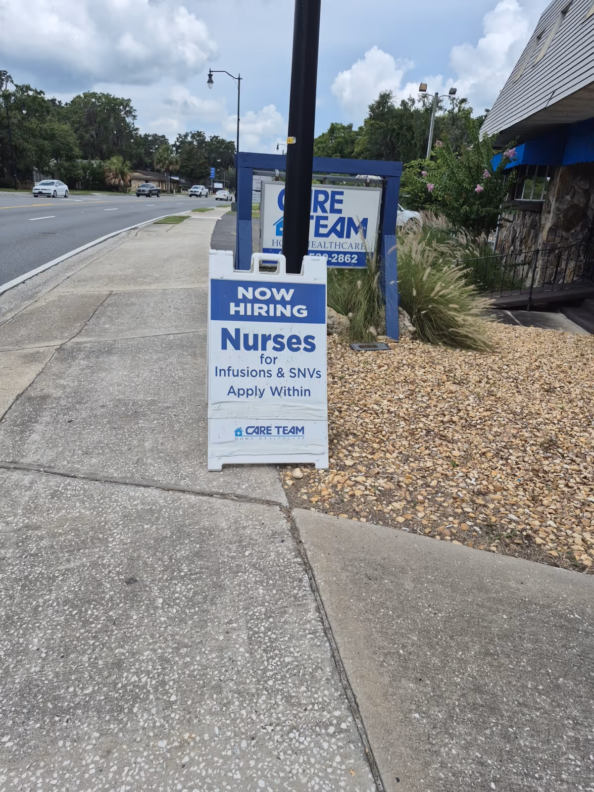 Street view showing a blue 'Now Hiring Nurses' sign outside a Care Team facility.