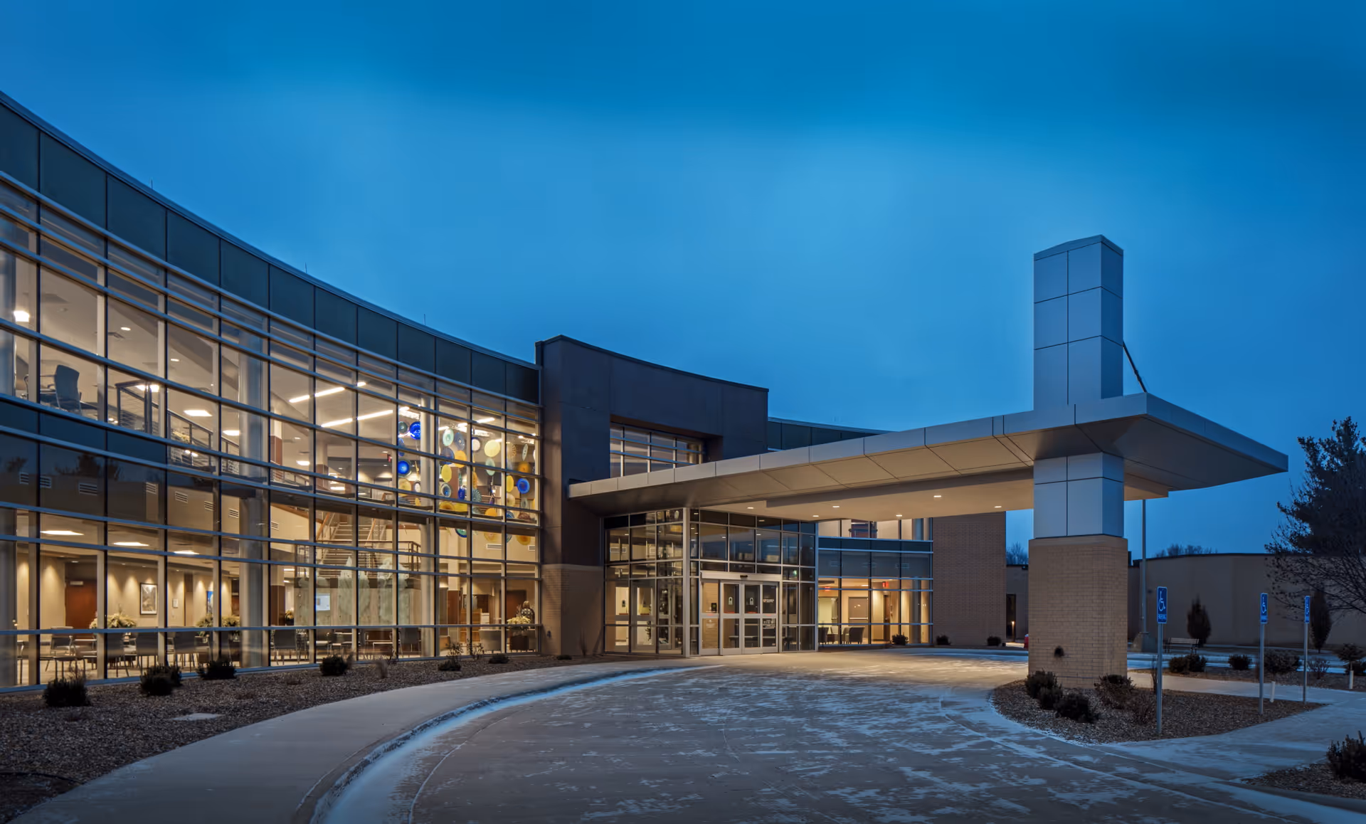 Exterior view of Shenandoah Medical Center's curved glass entrance at dusk.