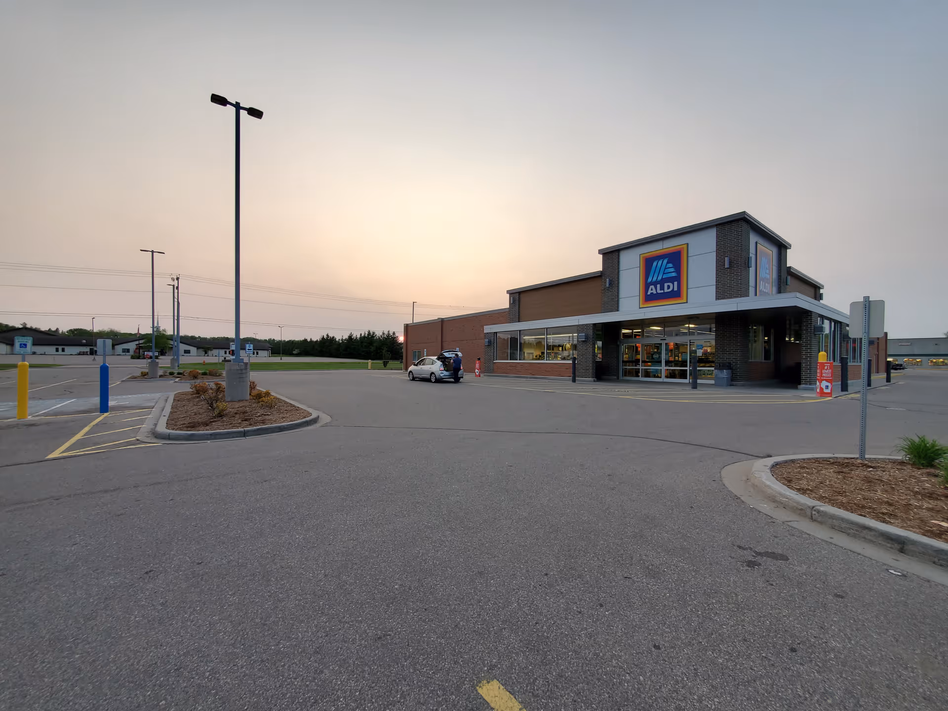 Exterior view of an Aldi storefront in a parking lot at dusk with a clear sky.