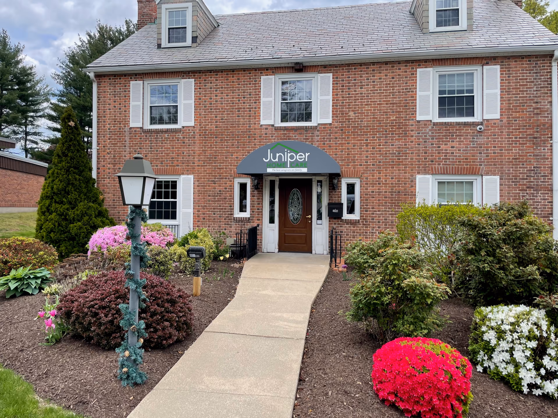 Brick senior living building with a landscaped front entrance and Juniper sign.