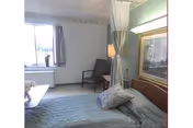 Bedroom in Seneca Nursing & Rehabilitation Center with a bed, chair, and window.