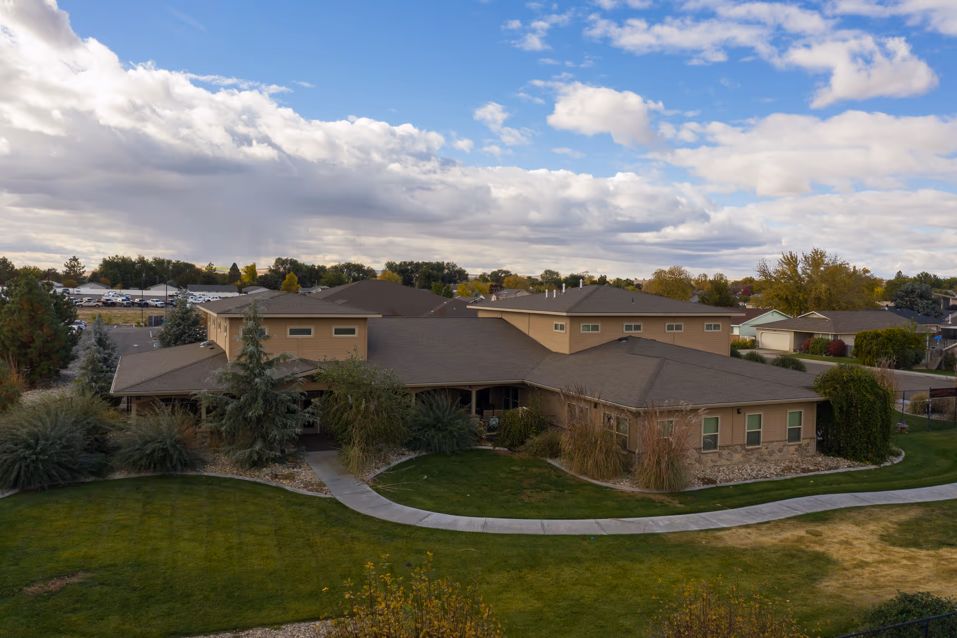 A single-story tan senior living facility exterior with a curved driveway and landscaping.