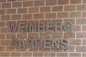 Weinberg Gardens sign mounted on a brick exterior wall.