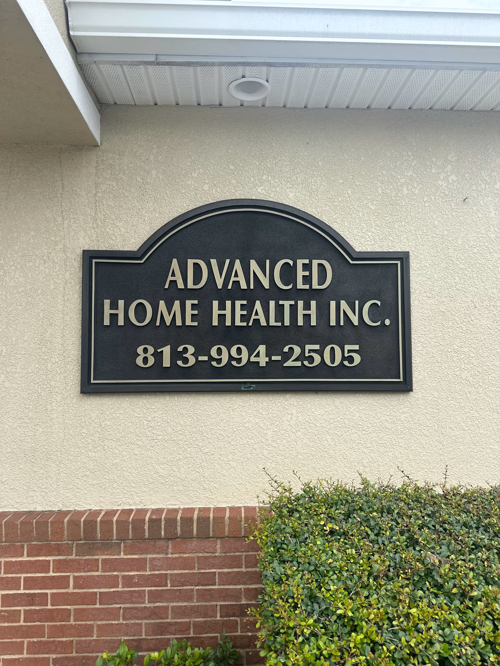 Front exterior sign for Advanced Home Health Inc. on a beige building wall.