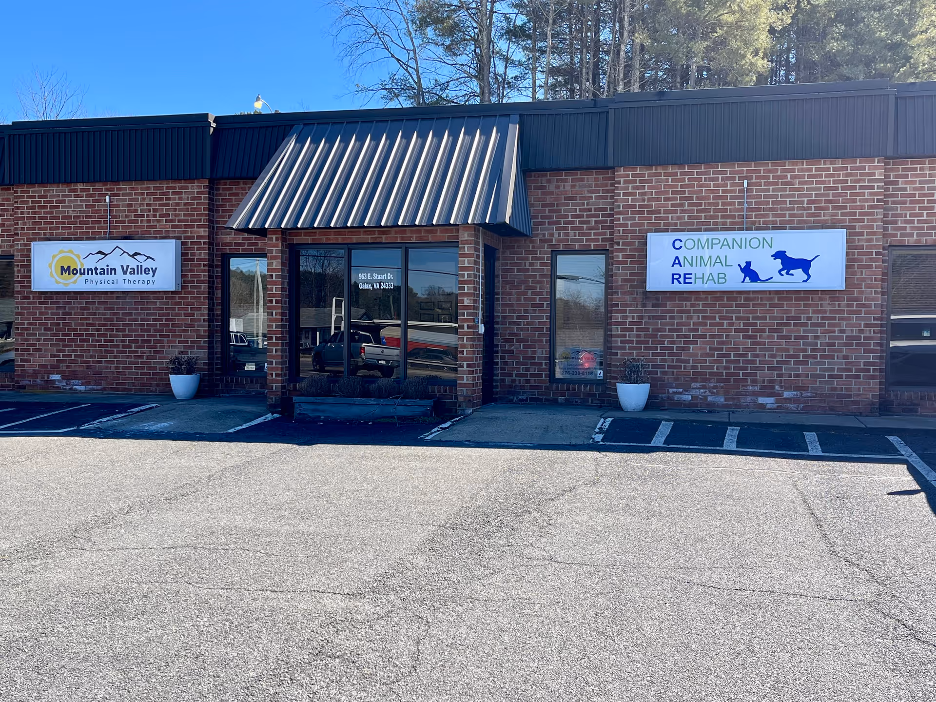 Brick storefront with signs, Mountain Valley Physical Therapy and Companion Animal Rehab, in a parking lot.