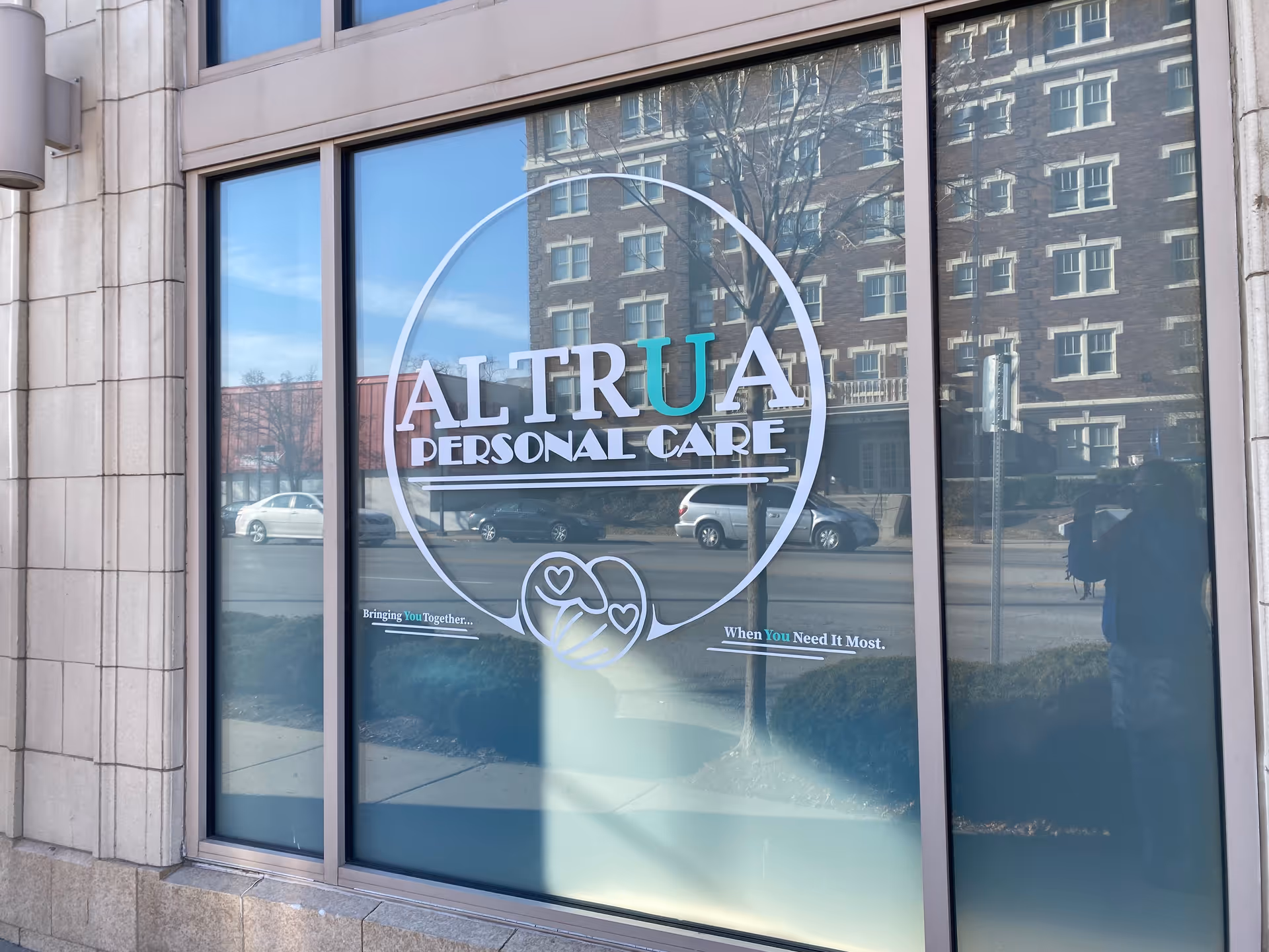Facade of a building with a large glass window displaying ALTRUA Personal Care logo.