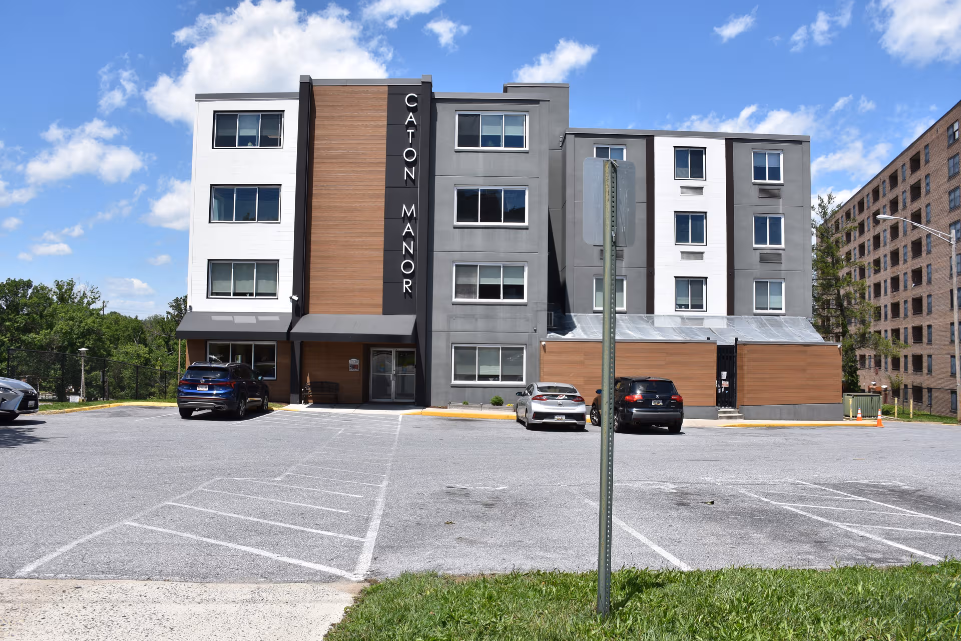 Exterior view of a modern multi-story senior living building with a parking lot.