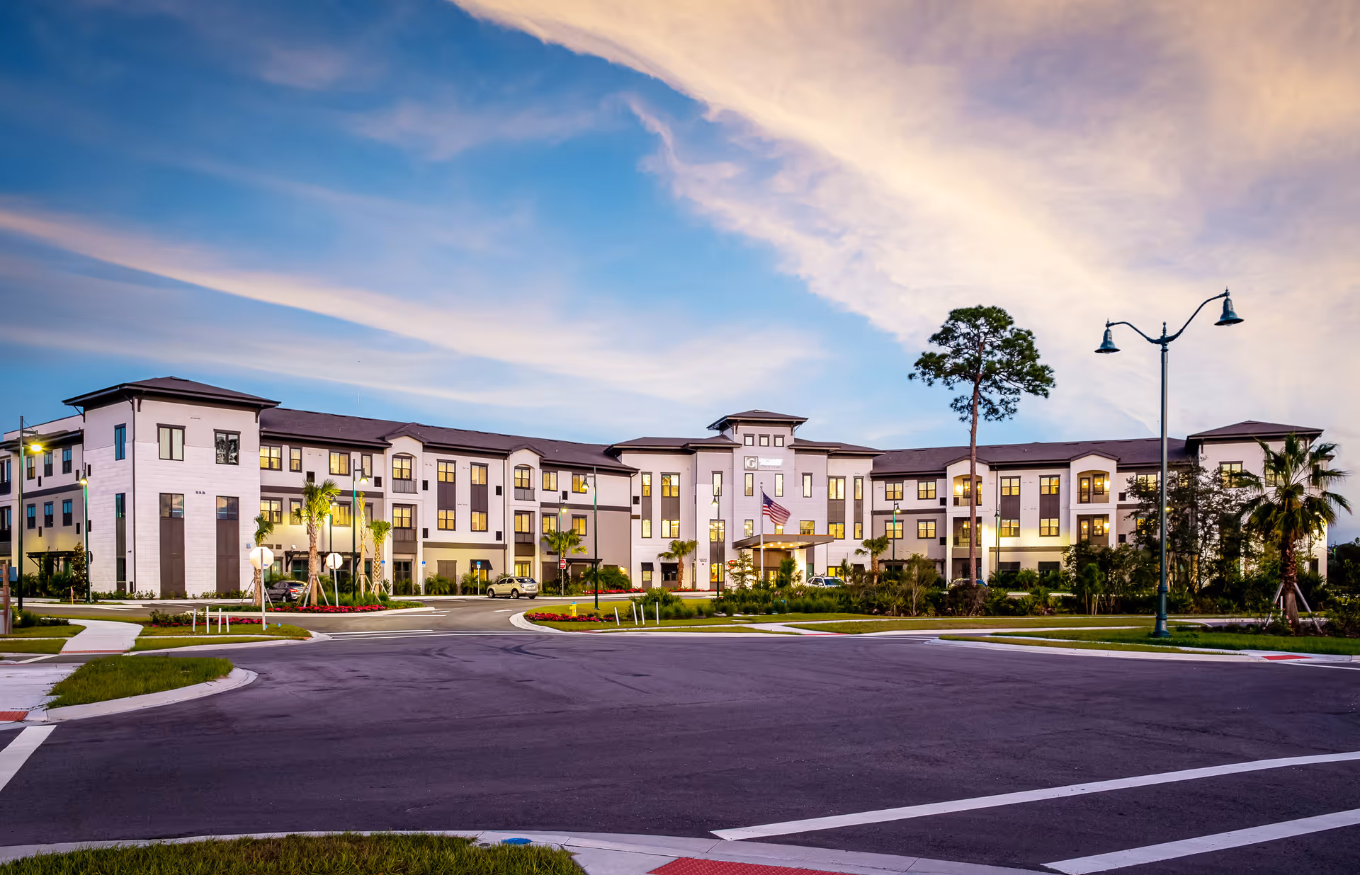 Exterior view of The Gallery at North Port: a modern, multi-wing senior living building at dusk.