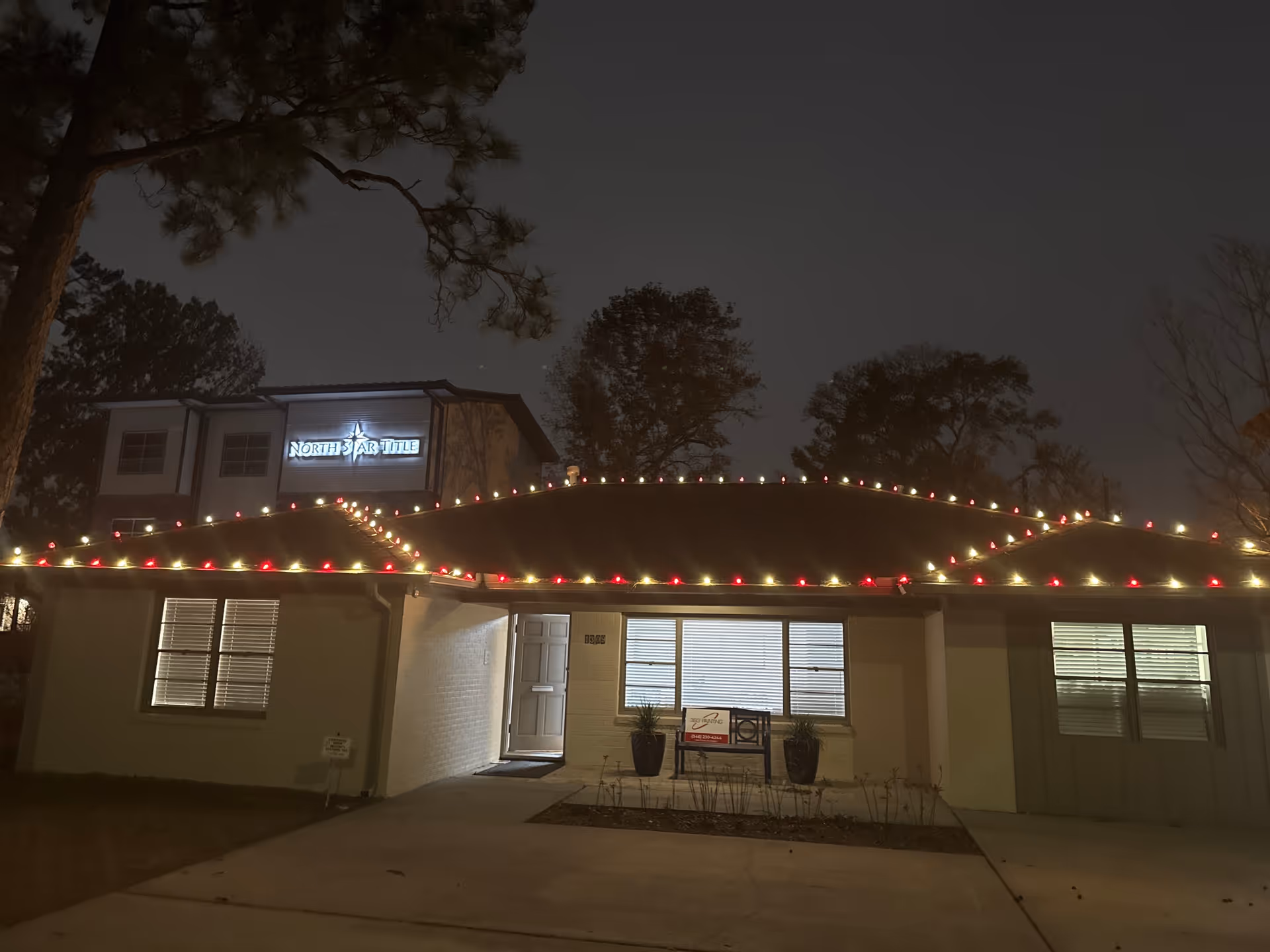 Night exterior of a single-story senior care building with string lights along the roofline
