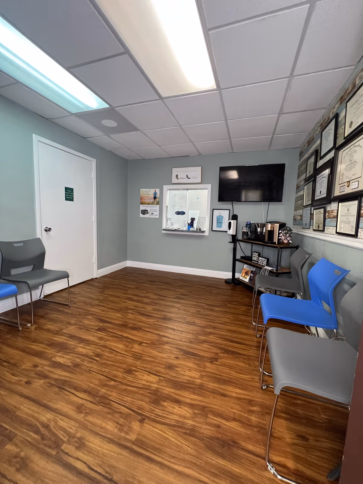 A waiting area with chairs along the walls, certificates, and a TV.