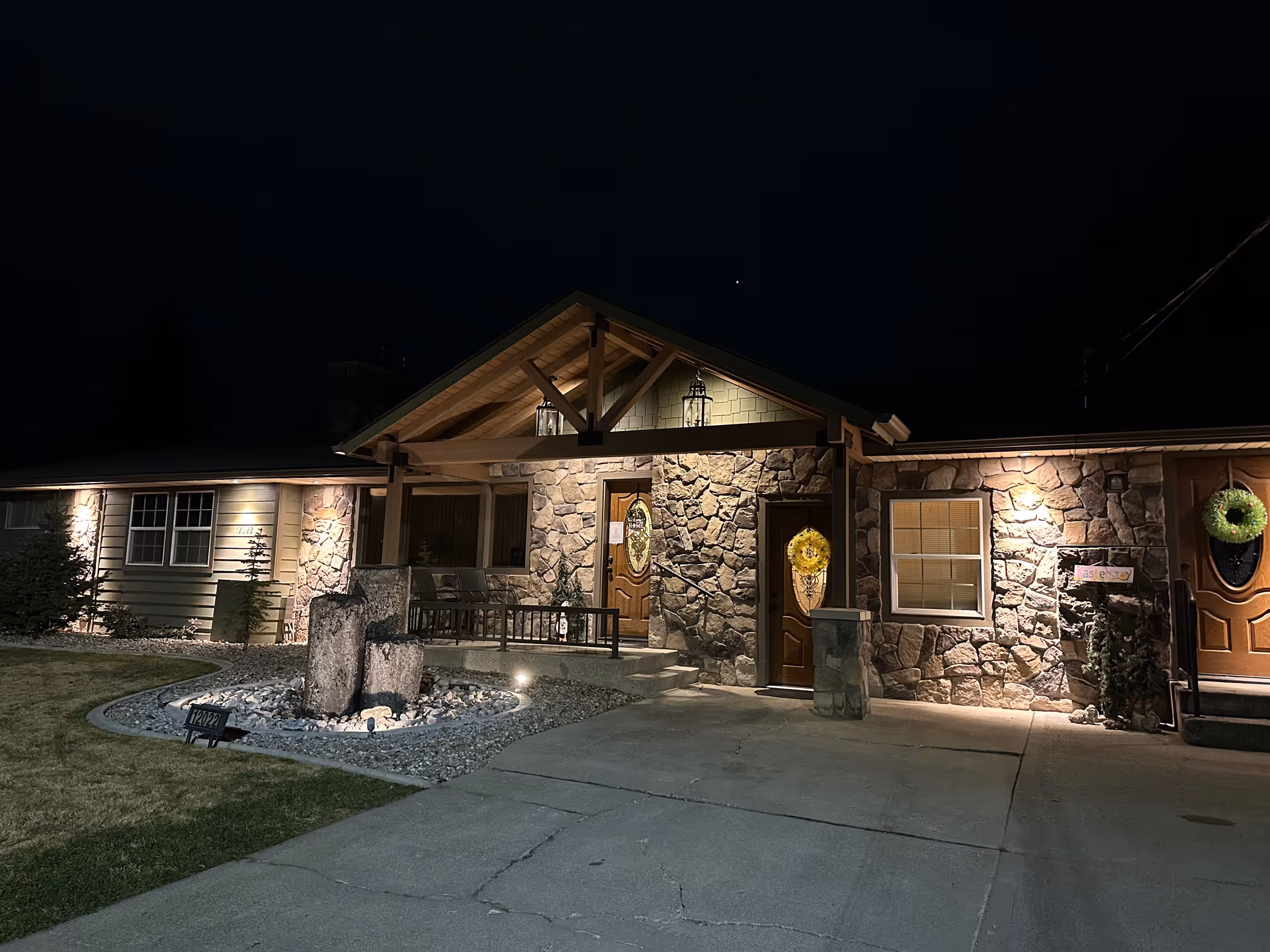 Night exterior of Valley Pines Retirement Home with stone facade, lit entry, wreaths on doors.