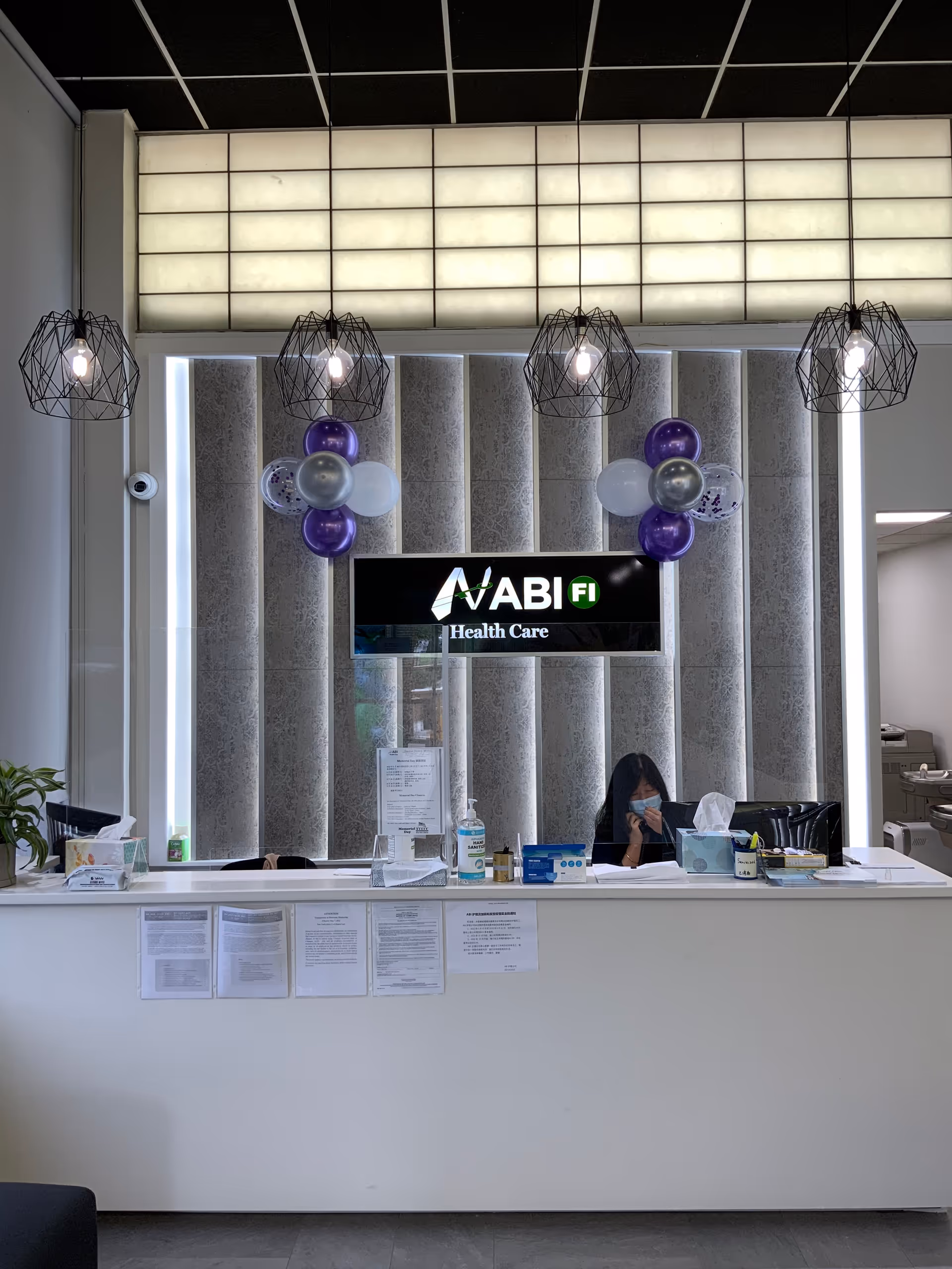 Reception desk with ABI Health Care sign and balloons in a lobby.