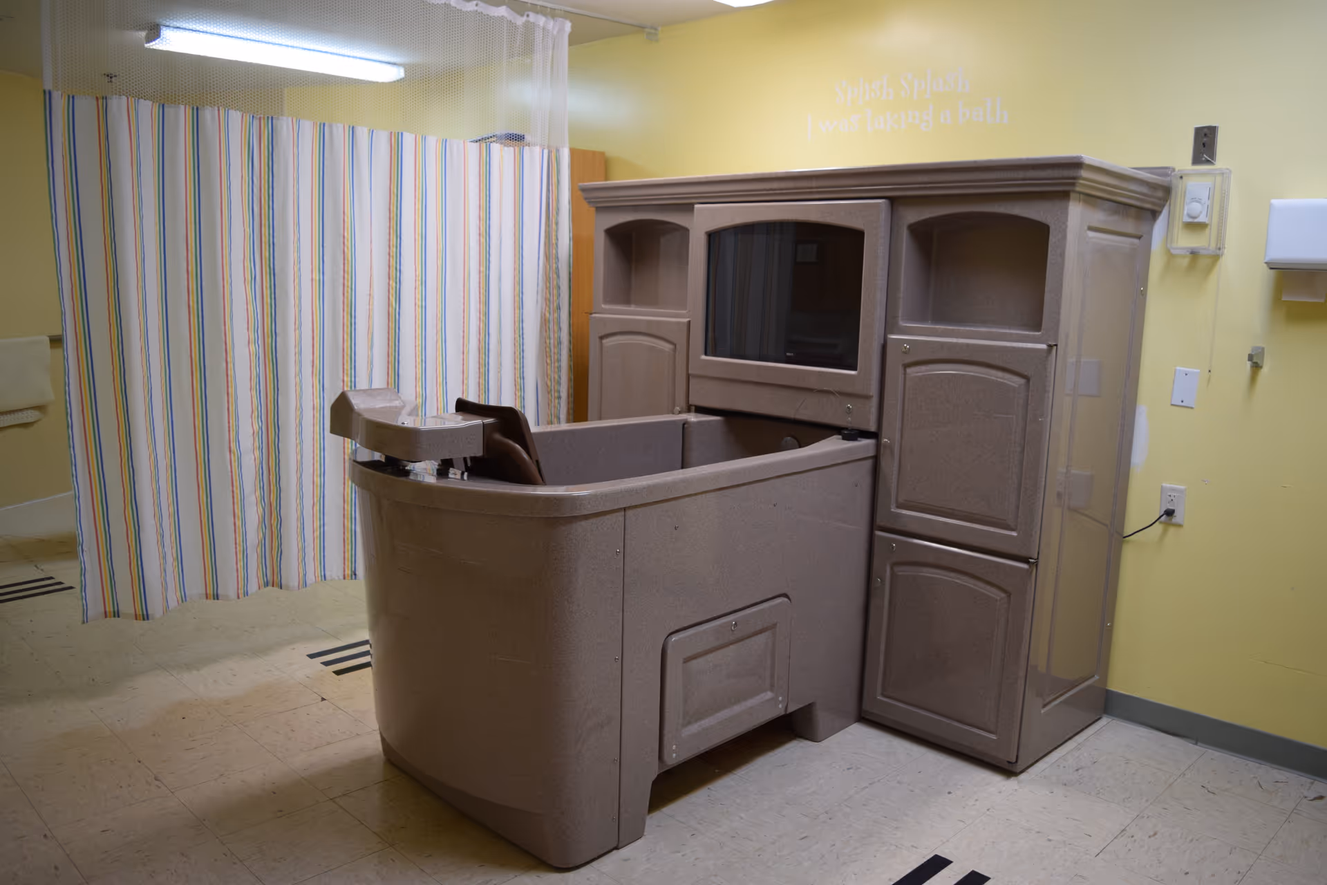 Yellow room with striped curtain and a large brown medical equipment unit.