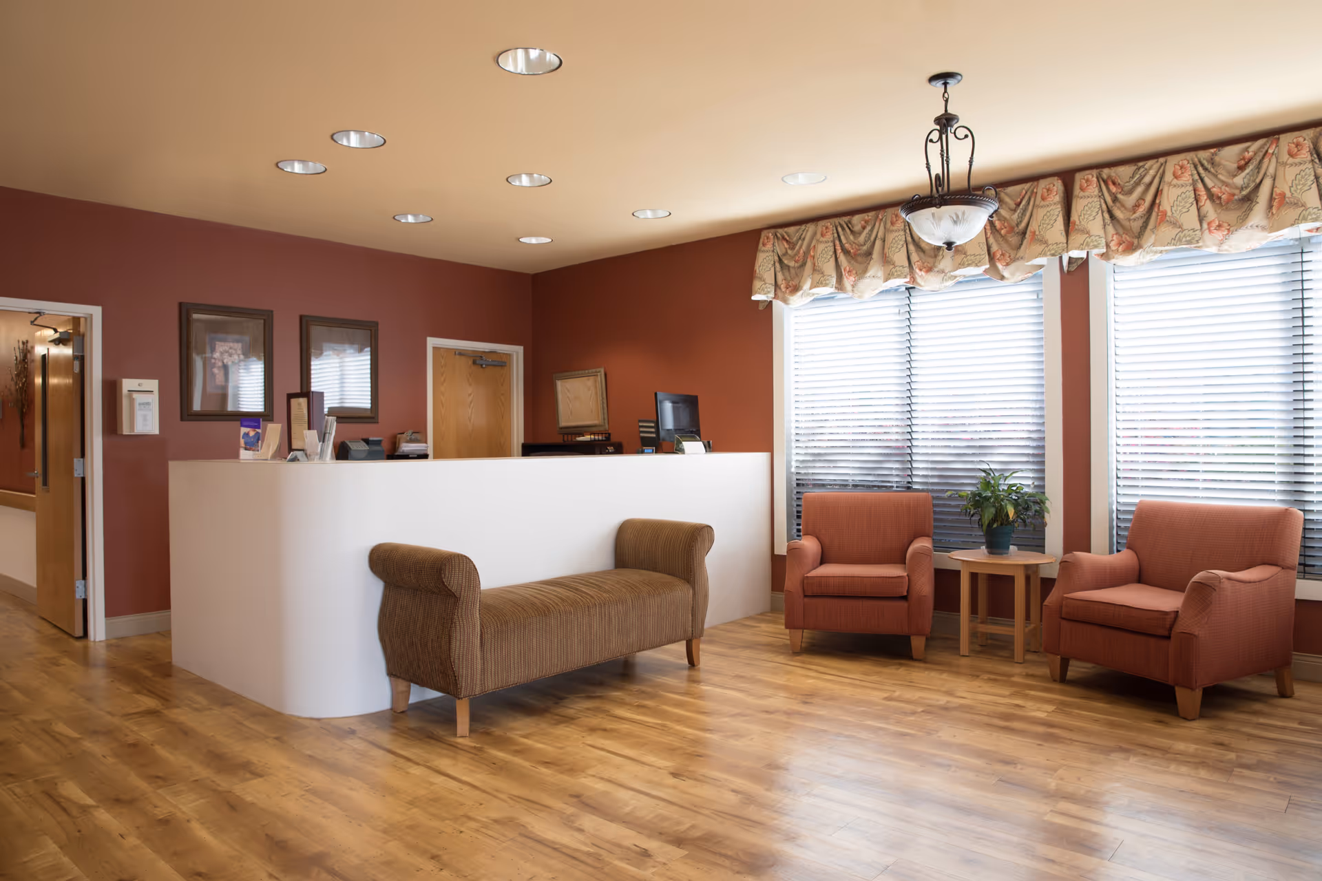 Reception area with white curved desk, burgundy walls, and orange lounge chairs.