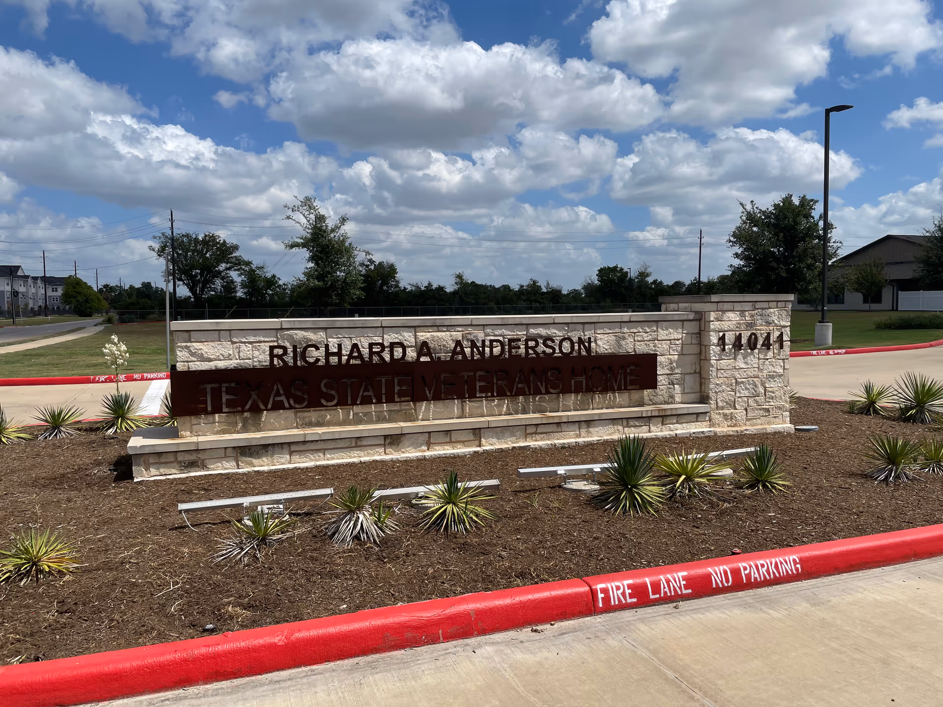 Stone entrance sign reads Richard A. Anderson Texas State Veterans Home with desert landscaping.