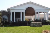Front view of Windsor Care Center with white columns, a covered entrance, and a green lawn.