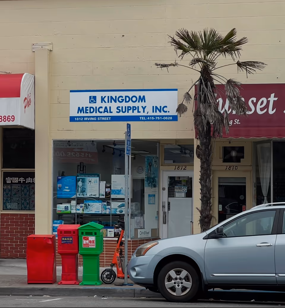 Storefront with Kingdom Medical Supply, Inc. sign, glass windows, palm tree, and parked car.