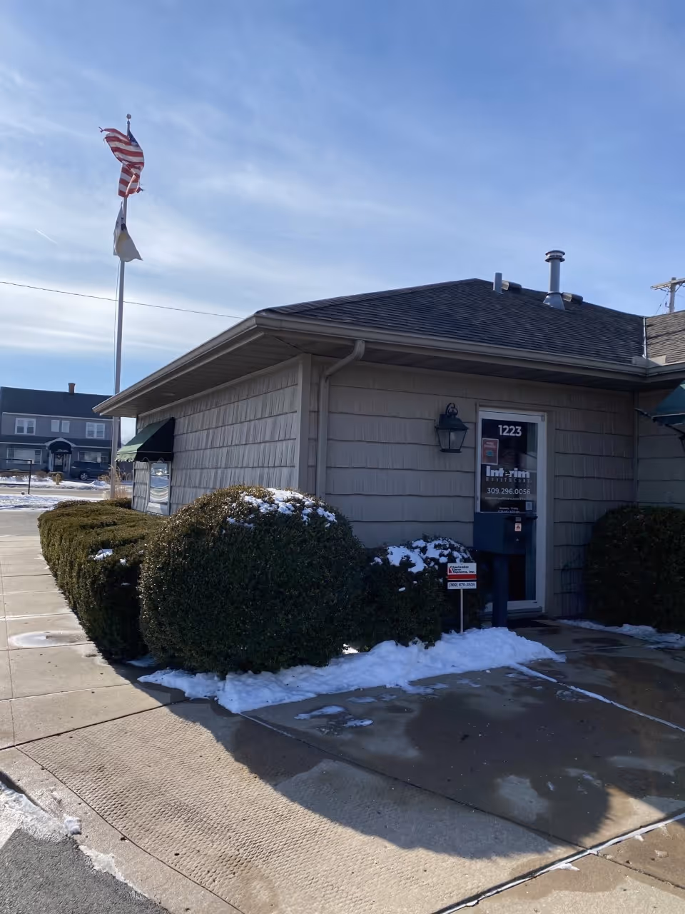 Exterior view of Interim HealthCare of Peoria building with flags and snow.