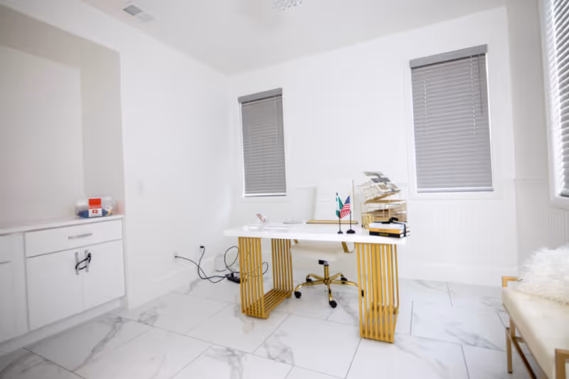 Bright white office featuring a desk, chair, files, and two windows in a clean interior.