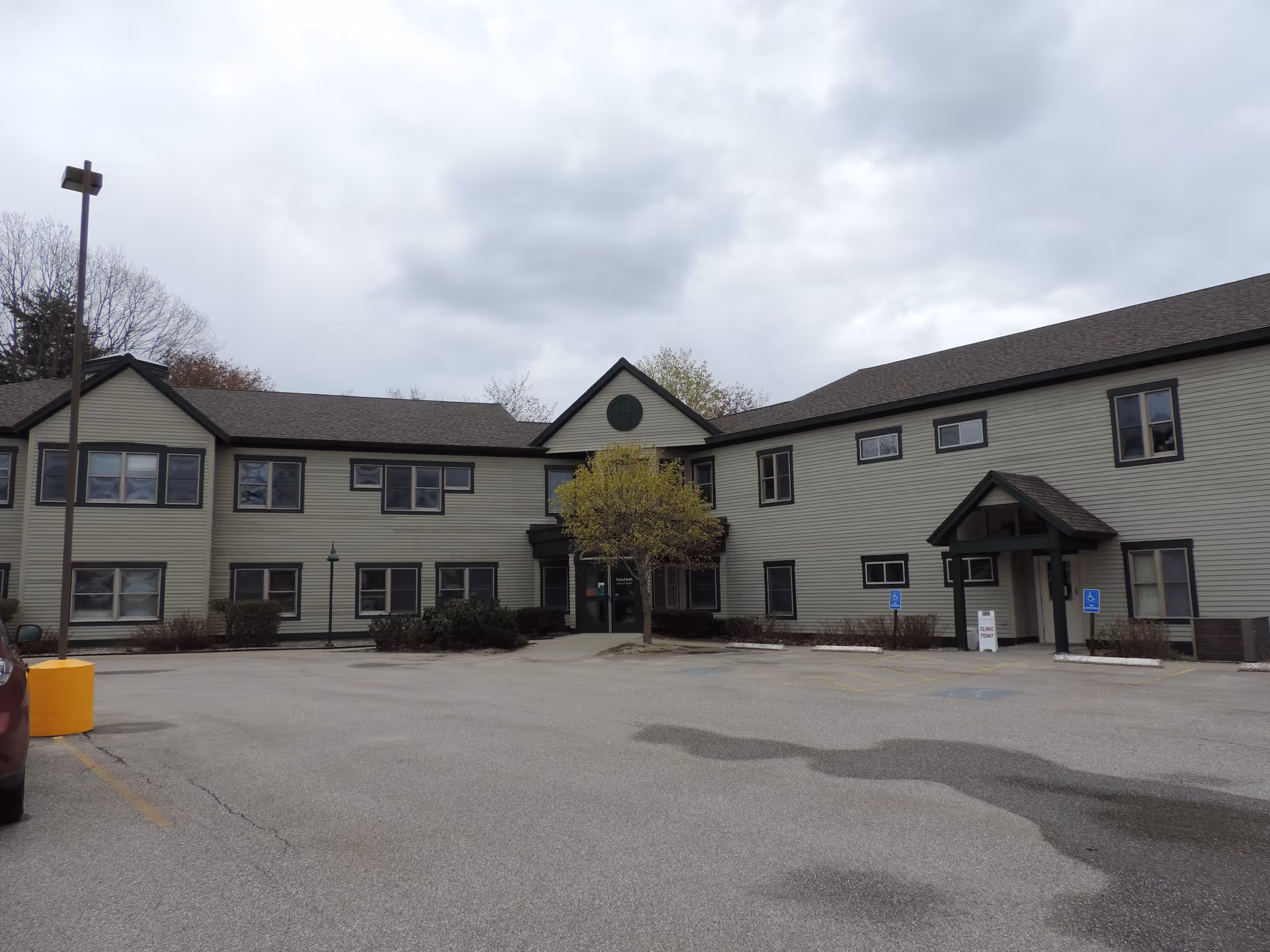 Two-story beige senior living facility exterior with a parking lot.