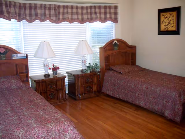 Two twin beds with matching wood headboards and nightstands in a bright, neat bedroom.