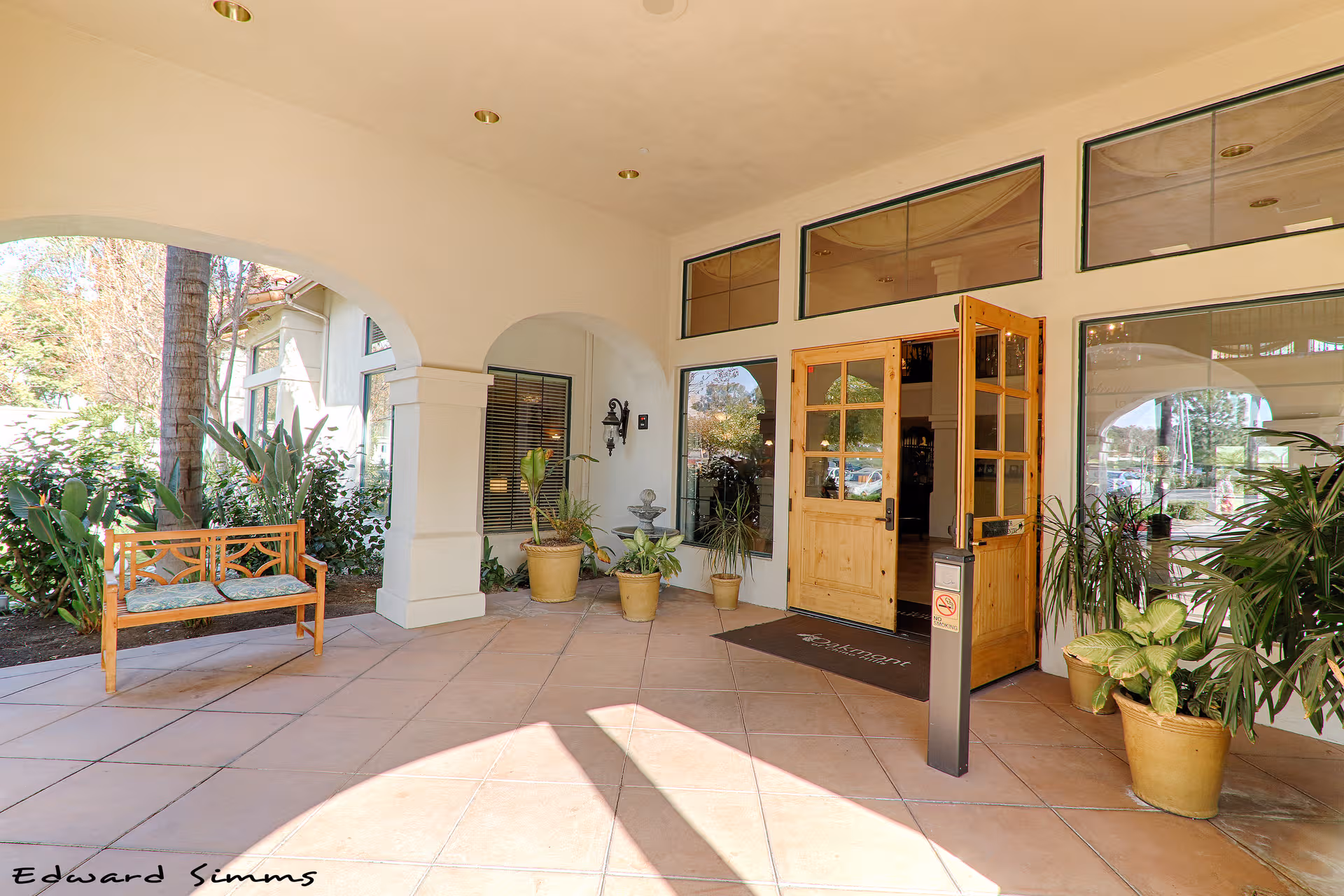 Covered entrance of Oakmont of Chino Hills with bench and potted plants.