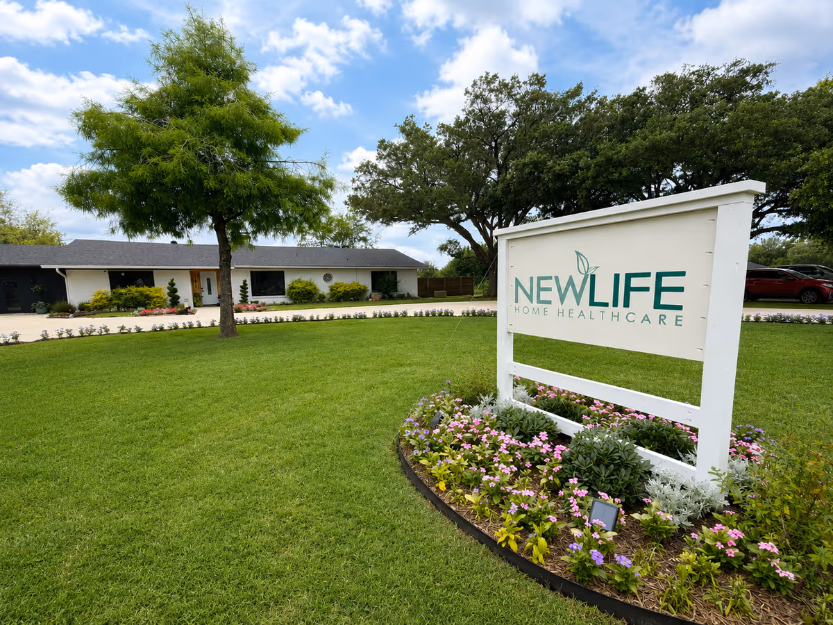 Well kept grassy lawn with a white sign reading NEW LIFE HOME HEALTHCARE, building in background.