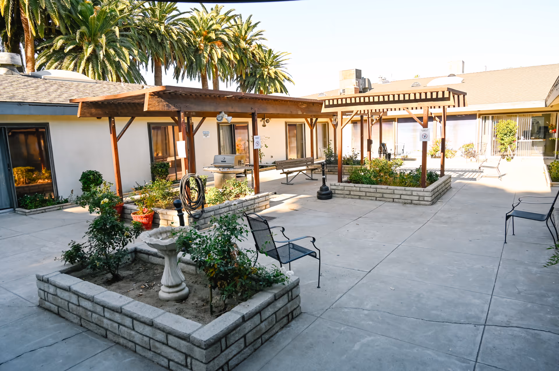 Outdoor courtyard of Woodcrest Post Acute & Rehab with pergolas, planters, and seating.