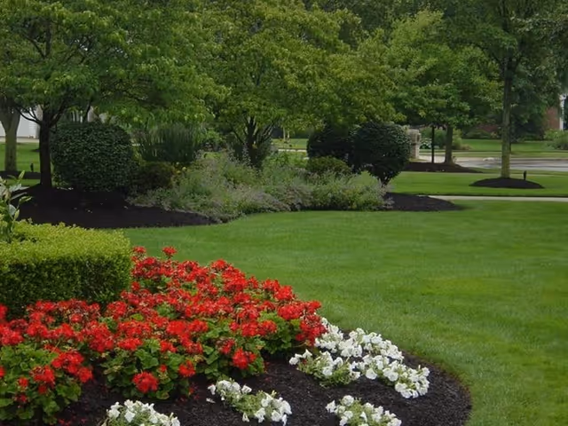 Beacon Heights Senior Living exterior with a well-kept lawn and colorful flower beds.
