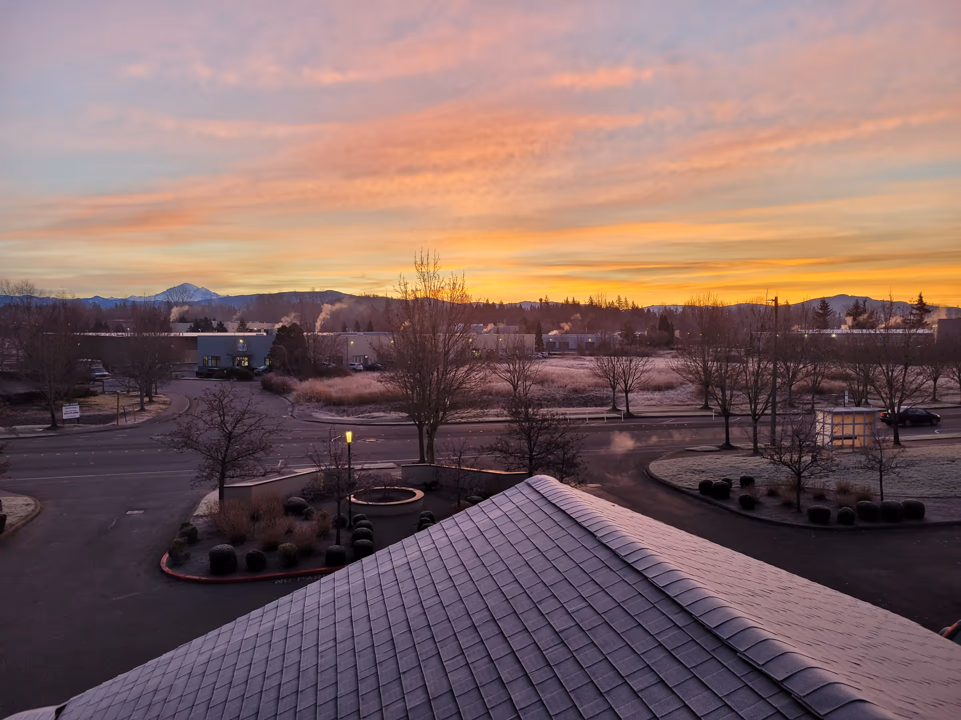 Sunset over Vintage at Bellingham campus, with roads, trees, and distant hills.