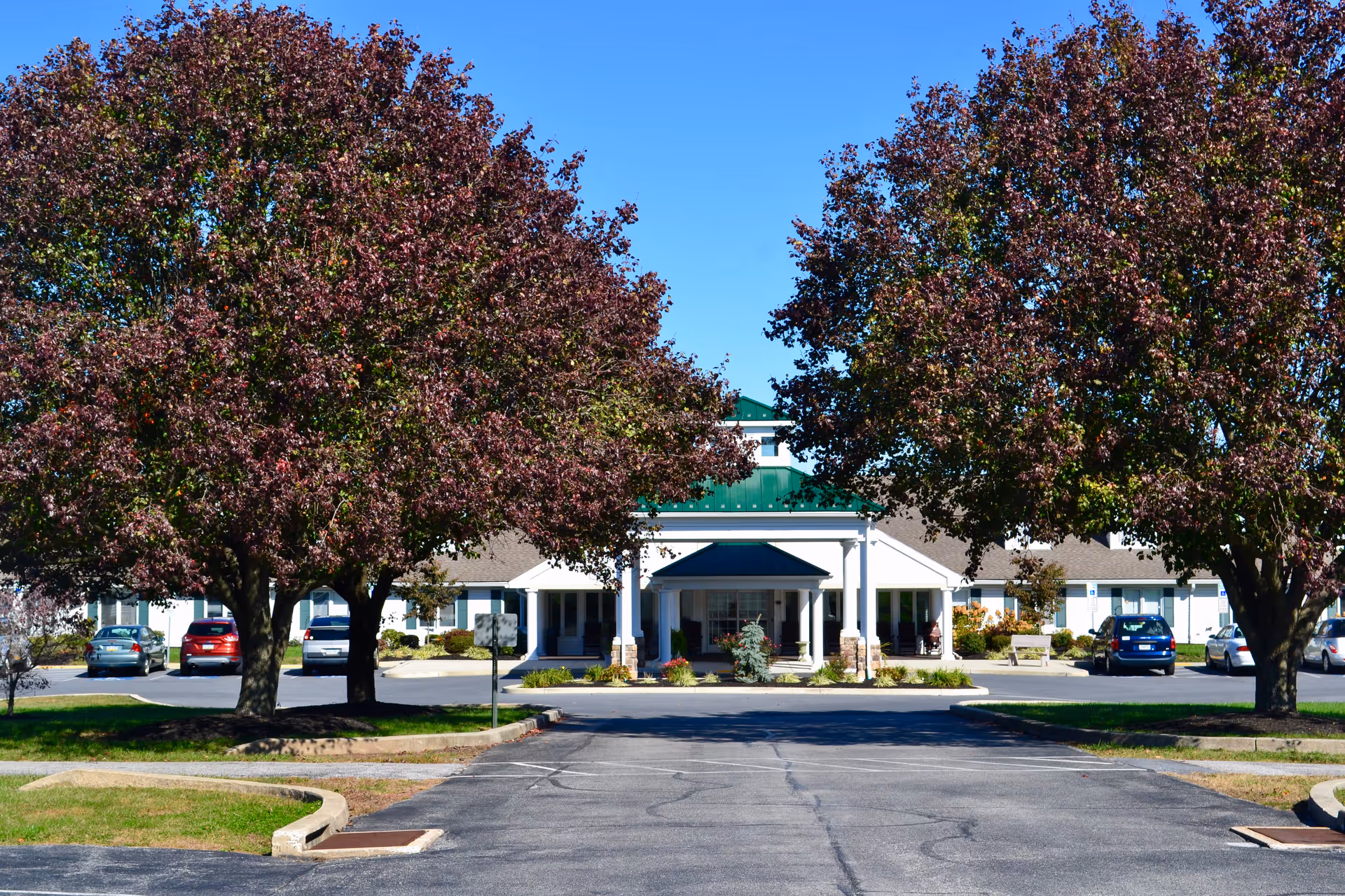 Front view of Providence Place Senior Living of Dover with trees and parked cars