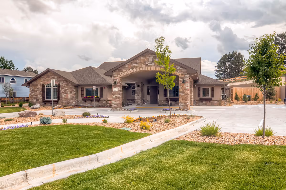 Stone-faced senior living facility front with manicured lawn and desert landscaping.