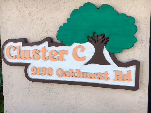 Exterior sign reading Cluster C and 9190 Oakhurst Rd with a green tree graphic.