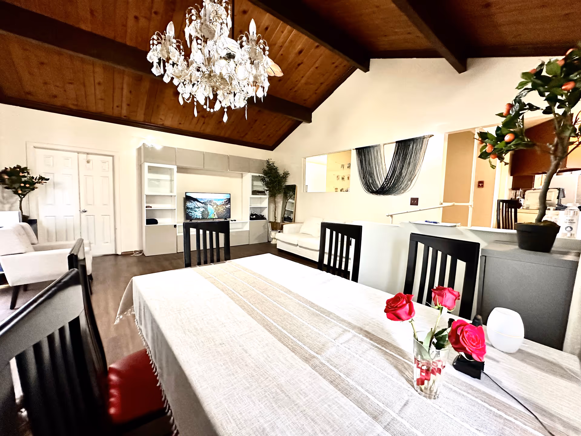 Spacious dining area with long table, chandelier, and living room seating in a modern villa.