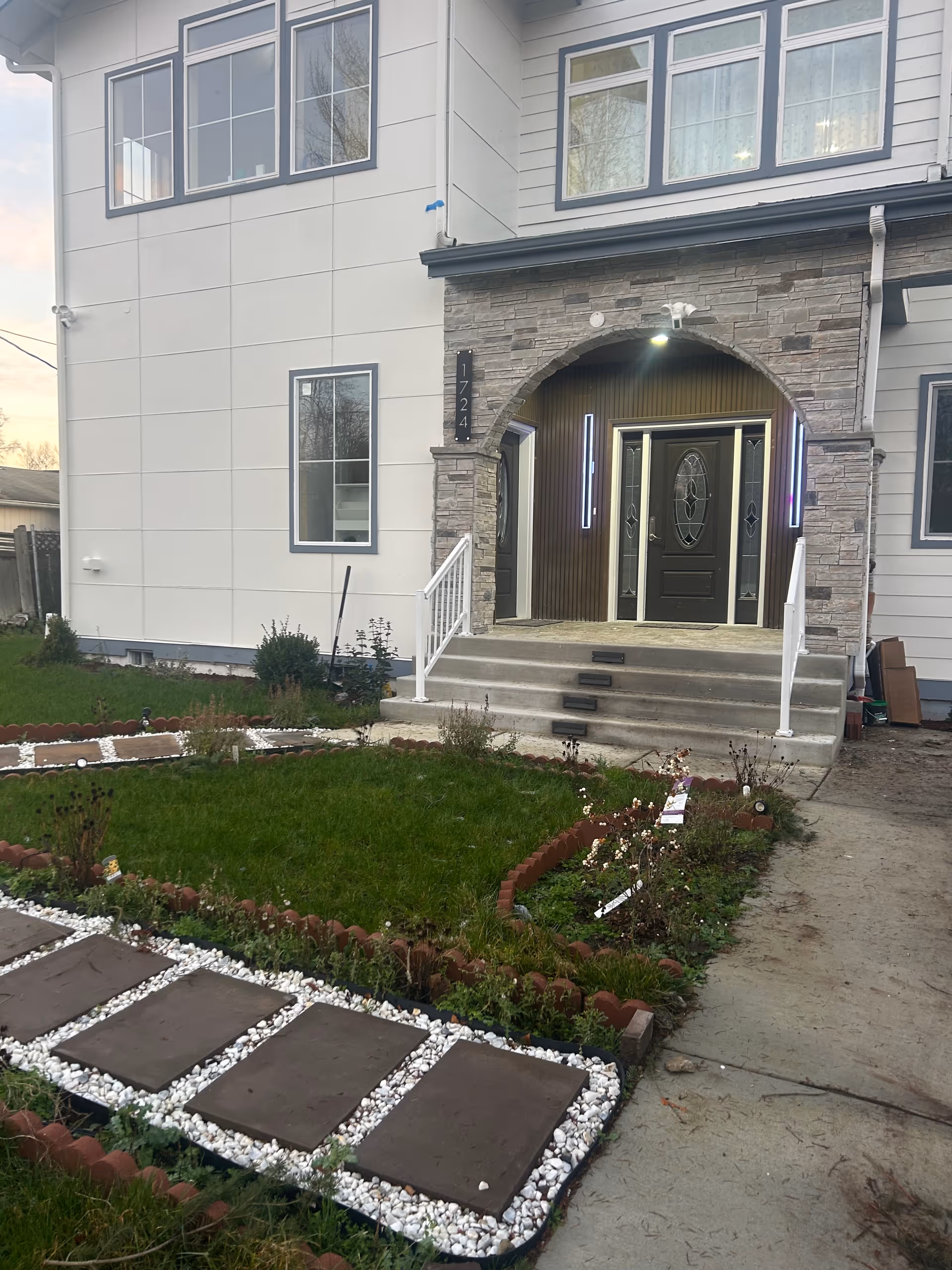 Exterior view of a two-story senior living home with a landscaped front yard and entry stairs.