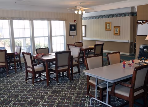 Interior dining room with tables, chairs, carpet, and large windows.
