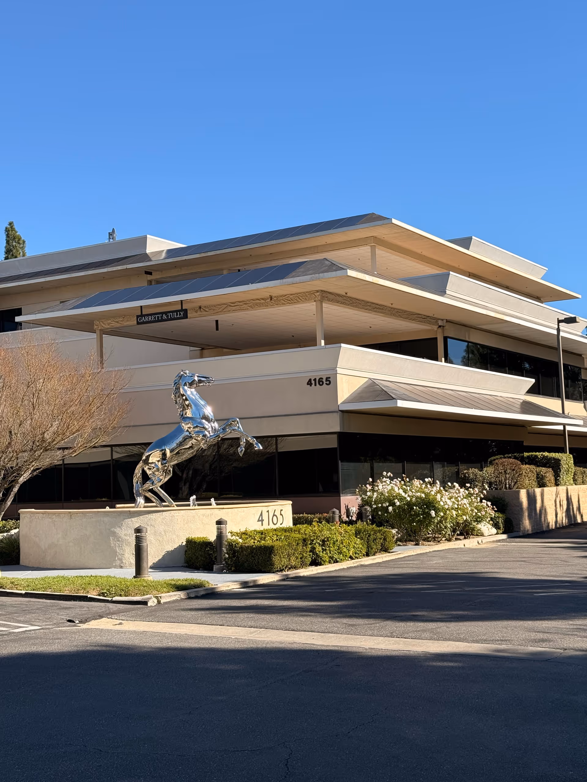 Modern multi-level facility exterior featuring a shiny horse sculpture at the entrance.